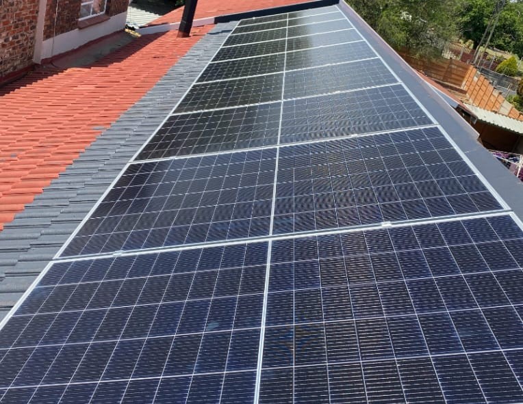 Technicians securing rooftop solar panels for grid-tied system