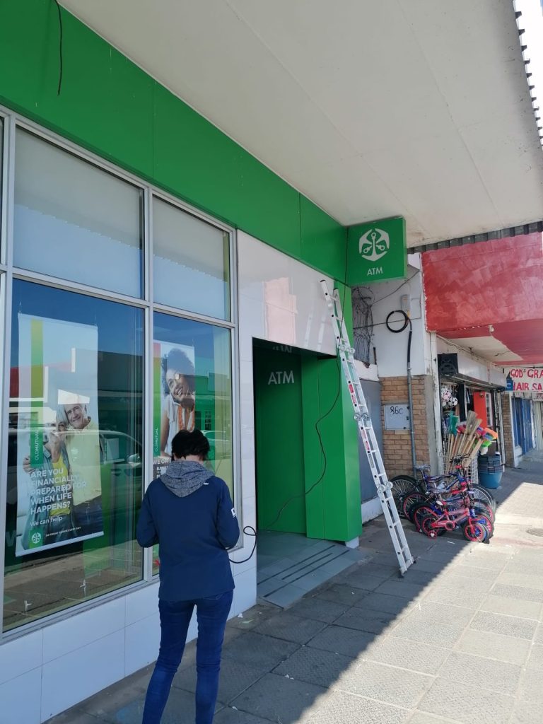 Replacing faulty light fixture above Old Mutual signage in Parys